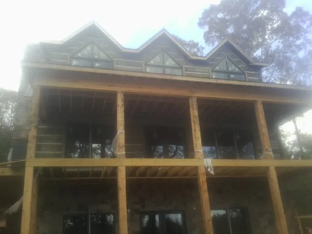 Dormers and porch framing on a large log home under construction — Roof Coating work by our crew in Britton