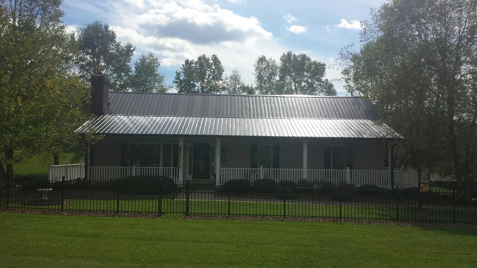Gray metal roof on a brick ranch with a full width front porch — Gutter Guard Installation work by our crew in Britton