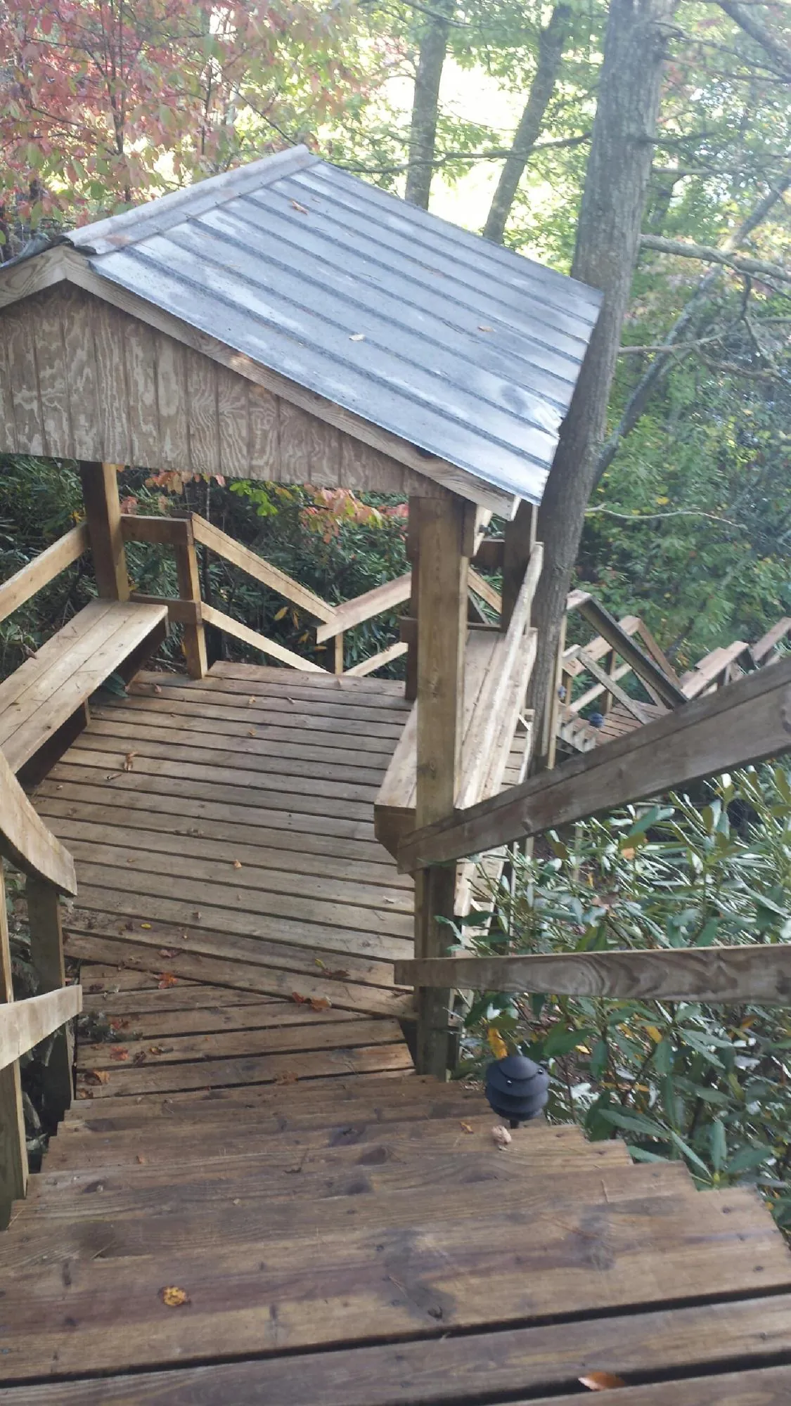 Metal roofed shelter over wooden steps on a wooded walkway — Skylight Repair & Installation work by our crew in Britton