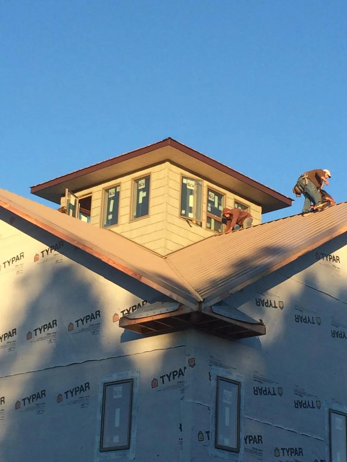 Roofers working around a rooftop cupola on a new metal roof at sunset — Roof Waterproofing in Britton by Roofing Brothers